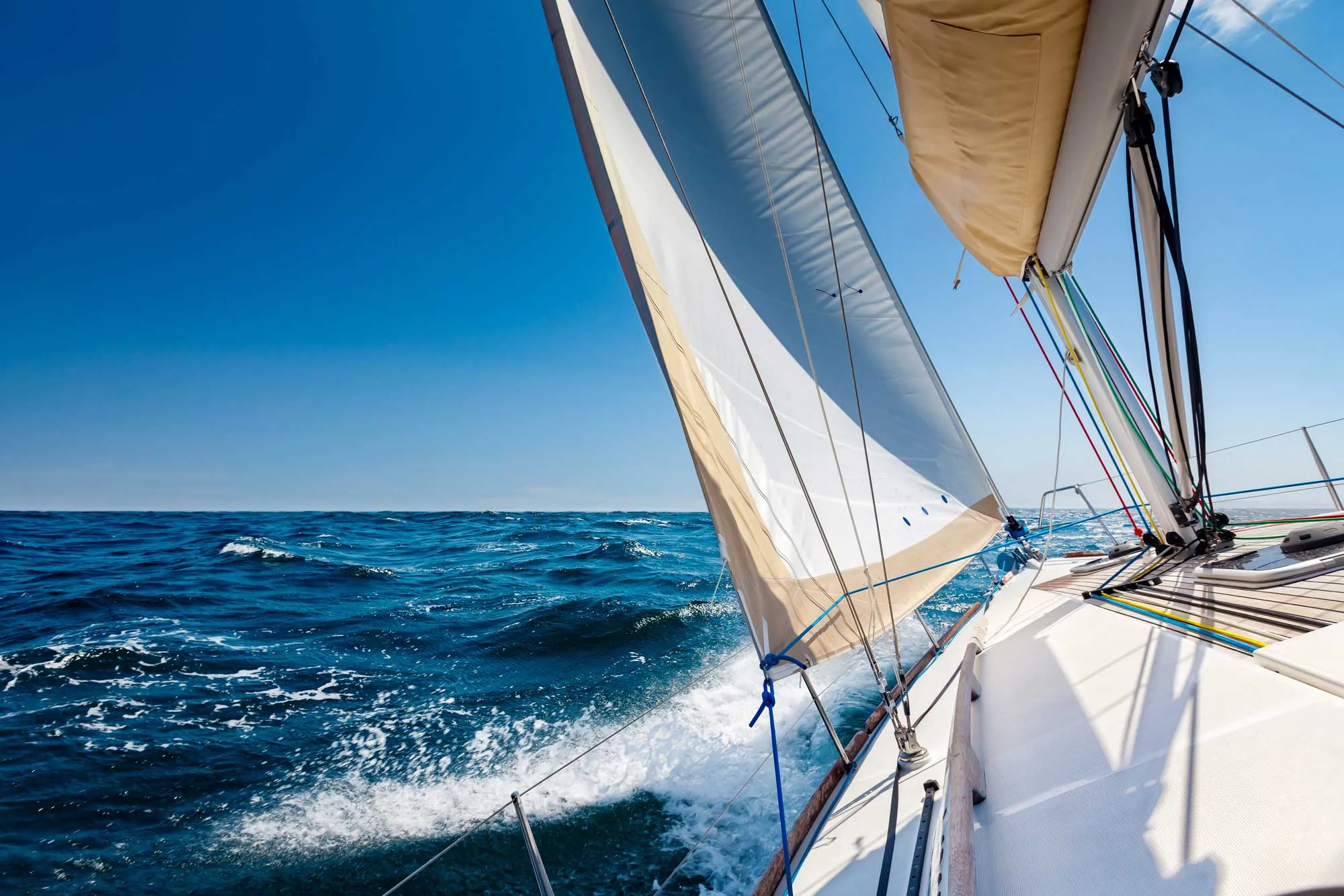 A boat gliding across the calm ocean waters and a vast horizon under a clear blue sky