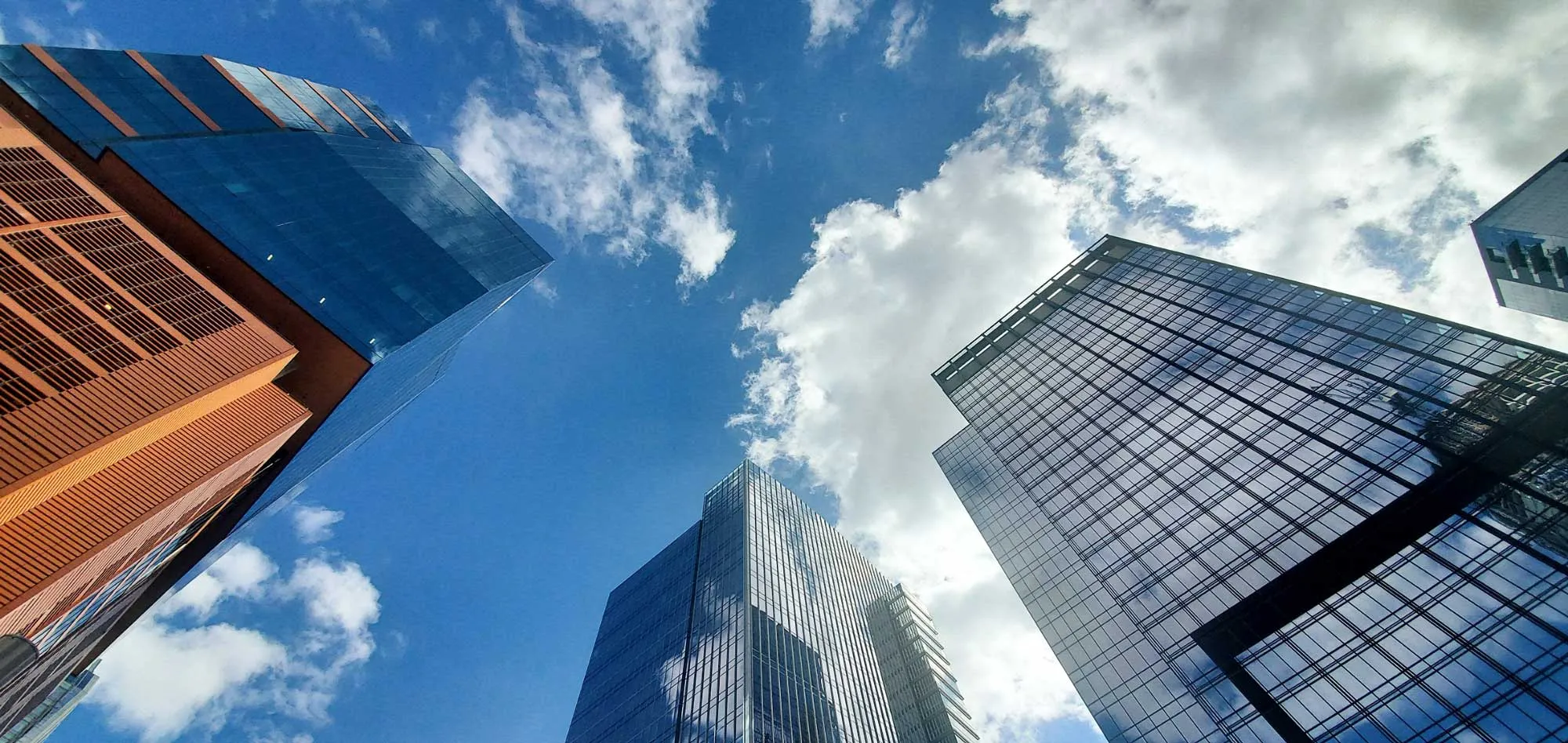 A tall building reaching toward a sky with white clouds